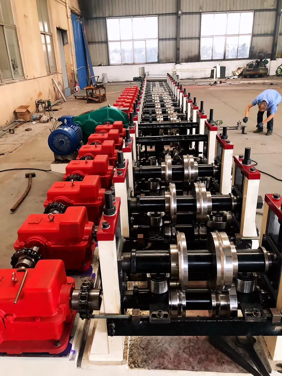 A row of roller shafts and red drive housings viewed along a machine