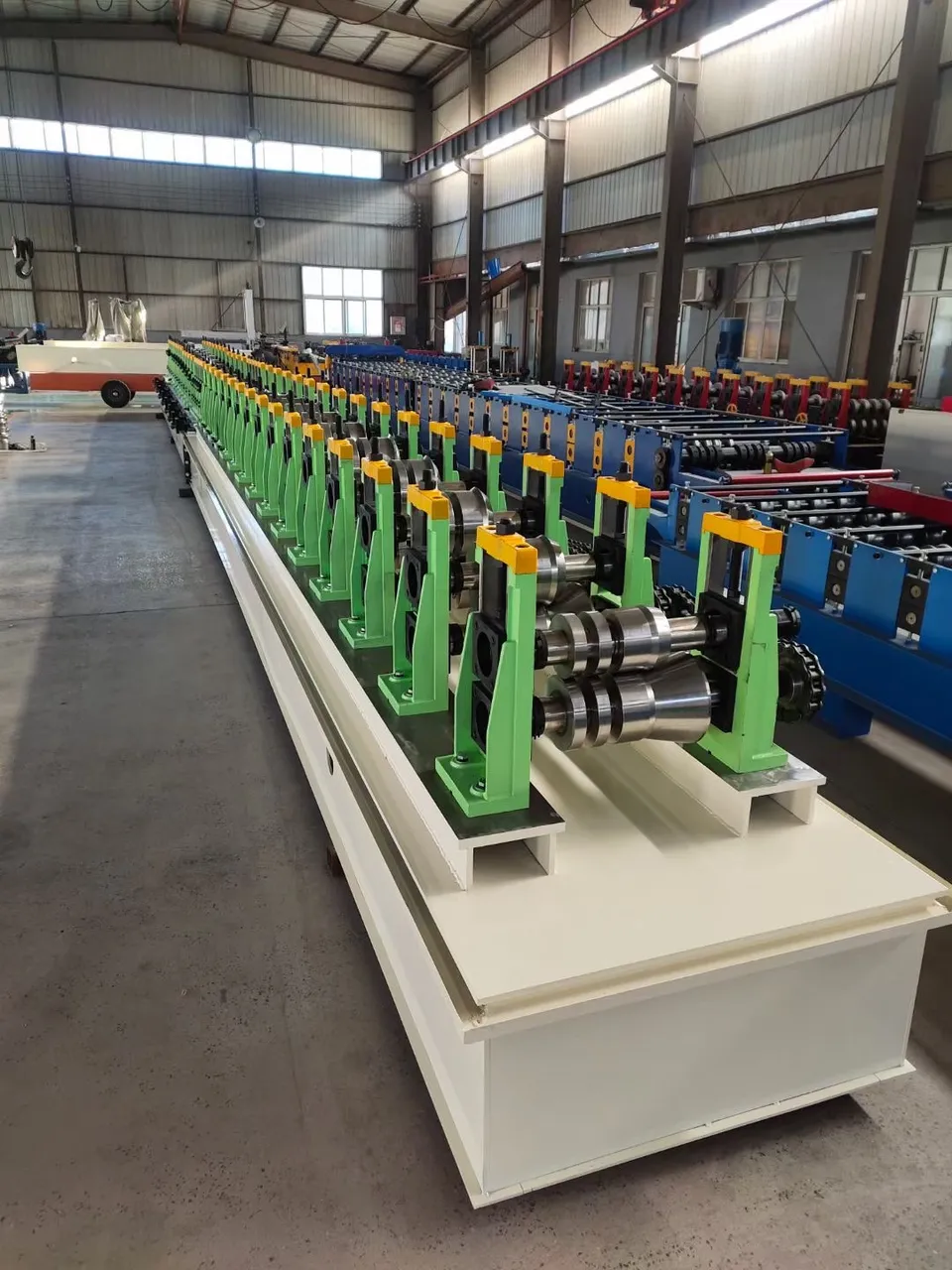 Green roller stands stretching through a steel-framed factory hall