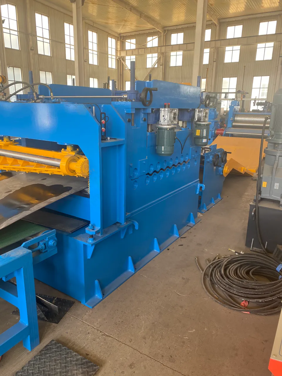 Workshop view of infeed rollers and forming housings. It is not a photograph of a named solar-strut model and does not show a solar farm.