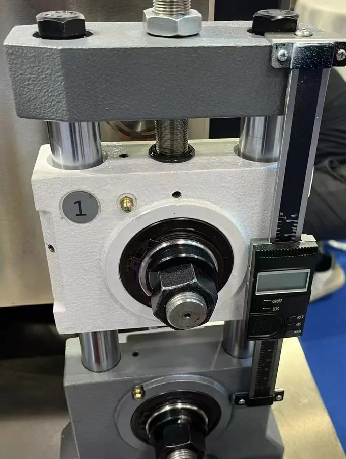 Close-up of a roller stand adjustment screw and scale from a supplied machine photograph